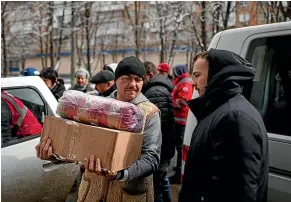  ?? AP ?? Residents of the besieged city of Mariupol receive humanitari­an aid from the Red Cross. Aid groups working in Ukraine say their job is being made harder by Russian attacks on cities and supply routes, as well as the huge number of people needing help.