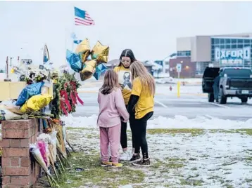  ?? NICK HAGEN/THE NEW YORK TIMES 2021 ?? Mourners bring flowers and balloons Dec. 1 to a makeshift memorial at Oxford High School in Michigan. A 15-year-old gunman killed four students the day before. The suspect’s parents also were charged in the case.