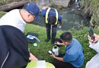  ?? ?? Ling (left) observes Johor DoE officers as they conduct a water sample test in Pasir Gudang on Tuesday.