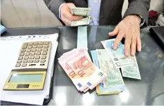  ??  ?? A money changer holds US dollar banknotes as he counts other currency banknotes at Grand Bazaar in Tehran, Iran. Currency exchange shops are refusing to sell US dollars because of the uncertaint­y as the rial has lost value in the past days. — Reuters...