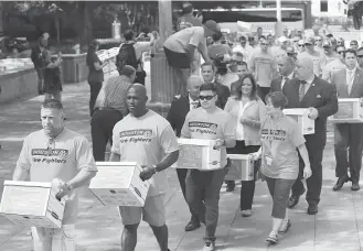 ?? Godofredo Vasquez / Houston Chronicle ?? Houston firefighte­rs carry boxes filled with more than 32,000 signatures to put equal pay on the ballot over to the City Hall Annex building in July.