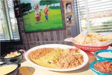  ?? AMY BETH BENNETT/SUN SENTINEL ?? Chicka-Chicka Boom-Boom enchiladas shown with queso, guacamole, chips, creamy jalapeño sauce and pico de gallo at Chuy’s Tex-Mex in Pembroke Pines.