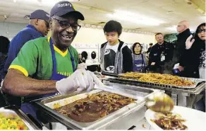  ?? DAVID BLOOM ?? Rotary Club volunteer Chinwe Okelu helps serve the annual community Thanksgivi­ng dinner at the Millbourne Laundromat, 109 Millbourne Rd. E., on Monday.