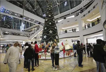  ?? KAMRAN JEBREILI / ASSOCIATED PRESS ?? Two people take a selfie earlier this month with a giant Christmas tree at a shopping mall in Dubai, United Arab Emirates. The UAE has long lured foreign workers with the promise of a tax-free life.