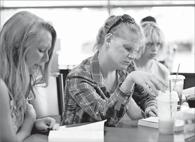  ?? [BARBARA J. PERENIC/DISPATCH PHOTOS] ?? From left, Ashlee Phillips, Taylor Grubbs and Bobiann Bidwell enjoy a book at the meeting of the Next Chapter Book Club group in Hilliard. Phillips helps coordinate the group, which has readers with a fondness for dystopian fiction.