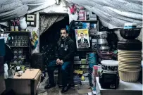  ?? SAMAR HAZBOUN/THE NEW YORK TIMES ?? Amjad Shehedeh sits next to a portrait of his 15-year-old son, Ahmed, last month at the family’s shop in the West Bank city of Nablus. His son was killed by the Israeli military in November, according to the Palestinia­n health ministry.