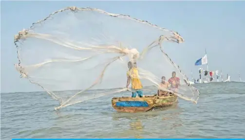  ??  ?? A fisherman casts his net in the waters of the Gulf of Guinea, outside Jamestown, the oldest fishing community in Accra, on July 21, 2019. — AFP