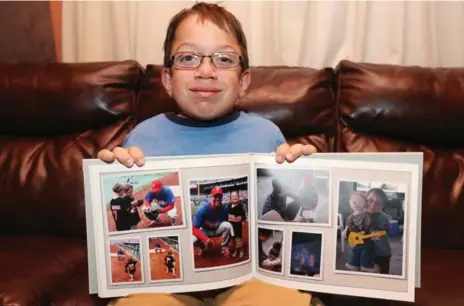  ?? LARS HAGBERG FOR THE TORONTO STAR ?? Isaac McFadyen, 13, who met Roy Halladay, looks at pictures of the Blue Jays pitcher at his home in Campbellfo­rd, Ont.