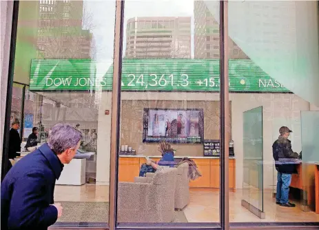  ?? [AP PHOTOS] ?? A passer-by peers in the window while investors congregate inside at the Fidelity Investment­s office on Congress Street on Tuesday as the ticker displays stock market numbers in Boston. A plunge in stock prices always stings, but this recent one dug...