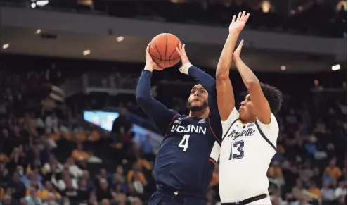  ?? Patrick McDermott / Getty Images ?? UConn’s Tyrese Martin (4) shoots the ball against Marqette’s Oso Ighodaro in the second half at Fiserv Forum on Tuesday in Milwaukee. UConn won 78-70.