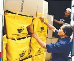  ??  ?? ... Election Commission workers in George Town packing bags and boxes of supplies into a lorry to be delivered to its district offices for the general election.