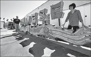  ?? Los Angeles Times/IRFAN KHAN ?? David Sevenson (left) and Kim Koga of the Museum of Neon Art in Pomona, Calif., hold up one of the dragon signs that once brightened Grauman’s Chinese Theatre in Los Angeles.