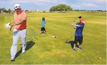  ??  ?? Notah Begay III moves to avoid the backswings of young golfers Ashton Knight, 6 (center) and Evan Knight, 9 (right) during a clinic that was part of Monday’s charity event that Begay hosted.