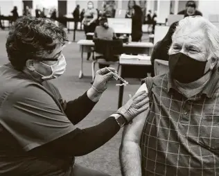  ??  ?? Hank Cortez receives the Pfizer vaccine from University Health’s Edna Fuster on Friday at a vaccinatio­n center set up inside the Wonderland of the Americas mall.