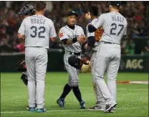  ?? TORU TAKAHASHI — THE ASSOCIATED PRESS ?? Mariners right fielder Ichiro Suzuki, center, talks to teammates while leaving the field for defense substituti­on in the fourth inning of Game 1 of the Major League opening series against the Athletics at Tokyo Dome on Wednesday.