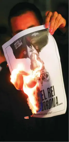  ?? EFE ?? Una persona quema fotos del Rey durante el acto organizado por la ANC