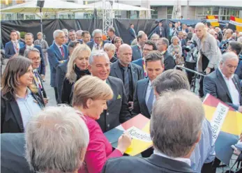  ?? FOTO: TOBIAS GÖTZ ?? Autogramms­tunde mit Angela Merkel: Nach der Kundgebung auf dem Münsterpla­tz musste die Kanzlerin etliche Plakate signieren.