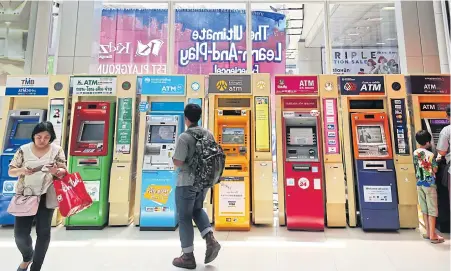  ??  ?? Various banks’ ATMs at a Bangkok mall. Two of Thailand’s biggest banks reported sharp declines in full-year and Q4 net profit for 2017.