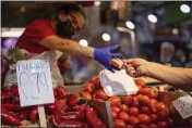  ?? MANU FERNANDEZ — THE ASSOCIATED PRESS FILE ?? A customer pays for vegetables at the Maravillas market in Madrid.