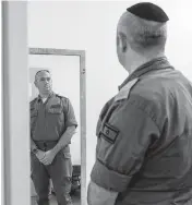  ?? HEIDI LEVINE for The Washington Post ?? Mordechai Porat inspects his uniform at the Shura Military Base.
