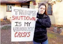  ?? Reuters ?? Cher Muzyk, wife of a government attorney impacted by the shutdown, holds a poster outside her home in Nokesville, Virginia, US, on Saturday.