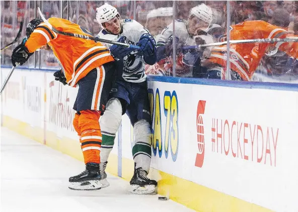  ?? — THE CANADIAN PRESS ?? Vancouver’s Nic Dowd is checked by the Oilers’ Adam Larsson in the first period of Saturday’s game in Edmonton.