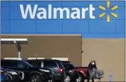  ??  ?? In this Nov. 18, 2020 file photo, a woman, wearing a protective face mask due to the COVID-19virus outbreak, wheels a cart with her purchases out of a Walmart store, in Derry, N.H.