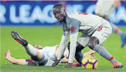  ?? KIRSTY WIGGLESWOR­TH THE ASSOCIATED PRESS ?? West Ham’s Robert Snodgrass, left, splays out as Liverpool’s Naby Keita keeps his eye on the ball at London Stadium on Monday.