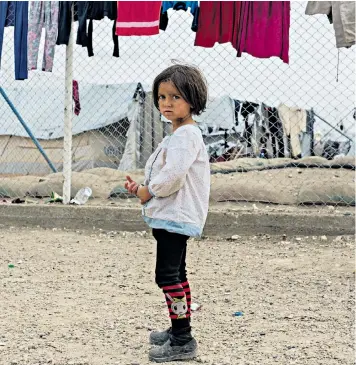  ??  ?? A girl stands in the section for foreign families at al-hol camp for people who lived under Isil; below children go to work at the market