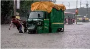  ??  ?? A man pulls his autoricksh­aw through a waterlogge­d street in New Delhi on Friday.