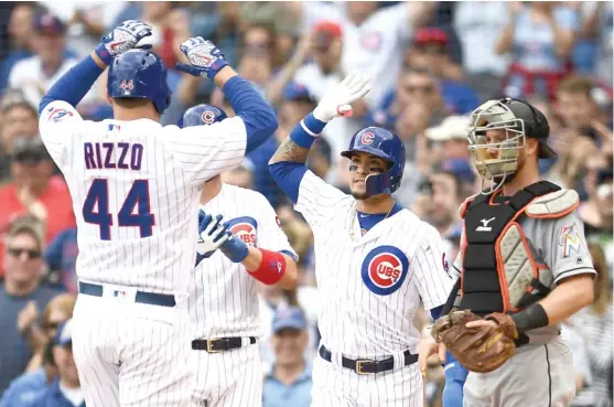  ?? STACY REVERE/ GETTY IMAGES ?? Javy Baez high- fives Anthony Rizzo after Rizzo’s three- run home run off Marlins starter Wei- Yin Chen in the third inning Wednesday at Wrigley Field.