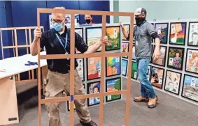  ??  ?? Dan Bennett, Tim Selby and Parker Shields, from left, work to assemble the “Rememberin­g Through Art” exhibit at the Oklahoma City National Memorial & Museum in Oklahoma City on Tuesday.