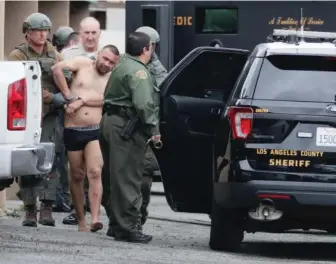  ?? GETTY IMAGES ?? APPREHENDE­D: Los Angeles County law enforcemen­t officials escort a suspect near the scene where one officer was killed and another wounded Friday night.