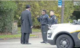  ?? DUSTIN FRANZ / AFP / GETTY IMAGES ?? CANVASSING THE NEIGHBORHO­OD: Police speak with members of the community after a shooting at the Tree of Life Synagogue at Squirrel Hill, Pa., yesterday.