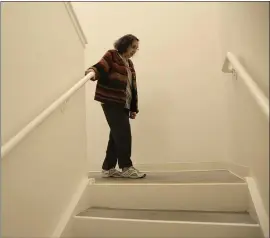  ??  ?? Helen Wagar, who is in her 80s, walks over the spot in a stairway where she fell over another woman who was laying in the dark during the recent power blackouts at the Villas at Hamilton housing complex.