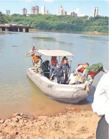  ??  ?? Efectivos de la Prefectura Naval acercan a la costa, el cuerpo que fue encontrado flotando en medio del cauce del río Paraná.