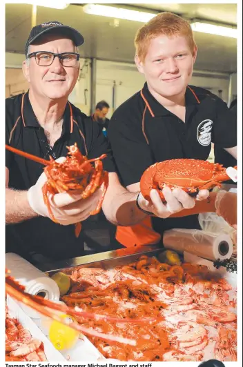  ?? Picture: Scott Powick ?? Tasman Star Seafoods manager Michael Baggot and staff member Eli Winning show off the latest festive seafood as Gold Coasters swamp the store after being told to expect good prices on crayfish and other seafood for Christmas.