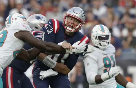  ?? Ap pHotos ?? ‘ROOM FOR IMPROVEMEN­T’: Patriots rookie quarterbac­k Mac Jones, center, is swallowed up by the Miami pass rush after releasing the ball on Sunday in Foxboro. Below, Jones hands his first NFL passing touchdown ball back to Nelson Agholor, who caught it during the second half.