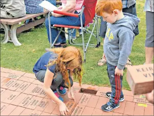  ?? DESIREE ANSTEY/JOURNAL PIONEER ?? Lexie Delaney, 9, and Cohen, 4, place an engraved brick in special memory of their grandfathe­r during the annual brick laying ceremony at the Internatio­nal Children’s Memorial Place on Sunday afternoon.