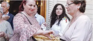  ?? Agence France-presse ?? ↑
Worshipper­s offer sweets after attending a mass at the Syriac Catholic Church of Mar Tuma in Mosul on Saturday.