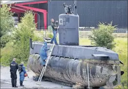  ?? [JACOB EHRBAHN/RITZAU] ?? Police technician­s inspect the amateur-built submarine UC3 Nautilus on a pier in Copenhagen after it was pulled from the sea recently off the east coast of Denmark.