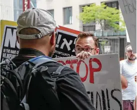  ?? Steve Gonzales / Houston Chronicle ?? Protesters stopped a man, who refused to say why he was recording, from filming them as they marched in front of HPD headquarte­rs on Saturday.