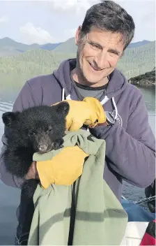  ??  ?? John Forde holds an orphaned black bear male cub that was taken to a recovery centre.