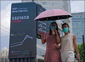  ?? (AP/Andy Wong) ?? Women walk past an electronic billboard showing China’s gross domestic product index on a commercial office building in Shanghai last month.