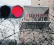  ?? REUTERS ?? The logo of Toshiba Corp is seen behind a traffic light at the company's headquarte­rs in Tokyo