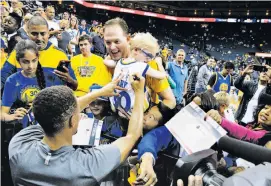  ??  ?? Greg Bell of Danville holds son Charlie, 5, up for Stephen Curry to sign his jersey before a Warriors preseason game against the Portland Trail Blazers.