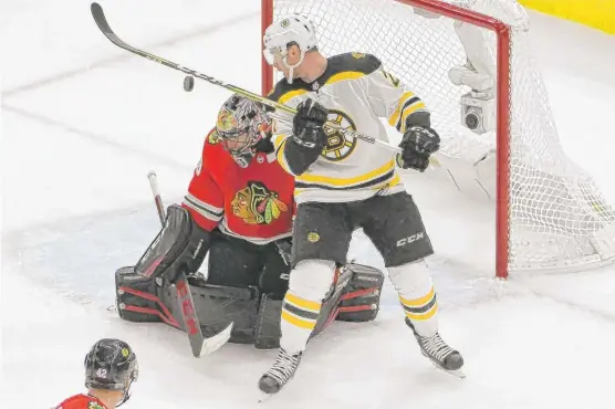  ??  ?? Bruins right wing Jordan Szwarz ( right) tries to tip the puck past Blackhawks goalie Corey Crawford during the first period Saturday at the United Center. | DAVID BANKS/ AP