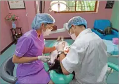  ?? CHARLOTTE PERT ?? A dentist inspects a woman’s mouth last year at a Phnom Penh dental clinic.