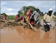  ?? (AP/Gideon Maundu) ?? Residents of Chamwana Muma village walk through floodwater­s after using a makeshift bridge to cross the swollen River Tana in Tana Delta, Kenya, on Wednesday.