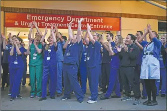  ?? (File Photo/AP/Alberto Pezzali) ?? National Health Service staff applaud in April outside the Chelsea and Westminste­r Hospital in London during the weekly “Clap for our Carers.” The applause takes place across Britain every Thursday at 8 p.m. to show appreciati­on for health care workers, emergency services, armed services, delivery drivers, shop workers, teachers, waste collectors, manufactur­ers, postal workers, cleaners, vets, engineers and all those helping people with coronaviru­s and keeping the country functionin­g while most people stay at home.